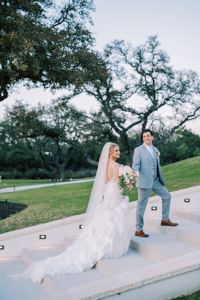 Groom holding bride's hand and leading her up a staircase