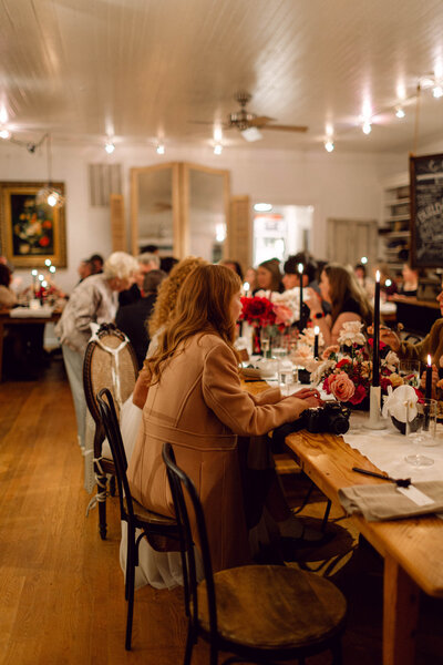 Wedding guests seated at a long dinner table under romantic string lights during an intimate indoor reception in a Richmond, Virginia home.