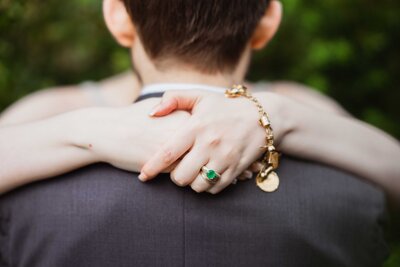 bride's hand with jwrery that holding groom's neck