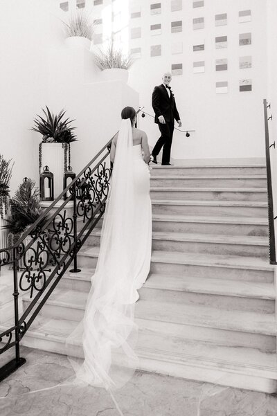 Bride walking up the stairs at the Four Seasons to meet the groom as he walks down the stairs
