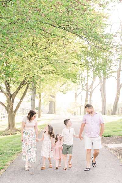 Family walking hand in hand under glowy green trees