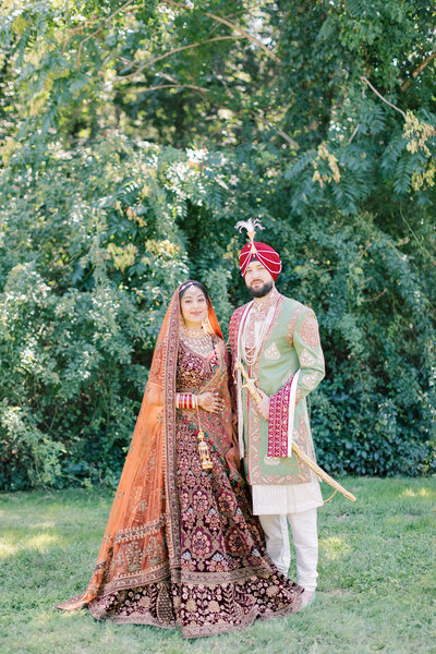 Bride and Groom Kiss on a Lush Green Lawn with Water and trees in the background