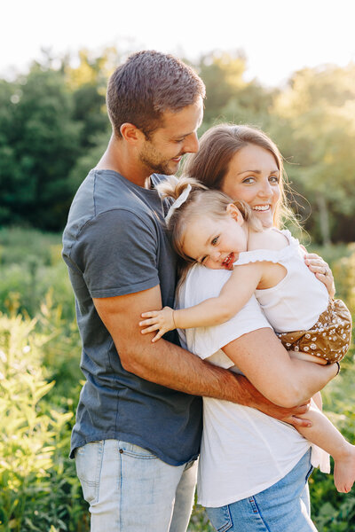 couple holding toddler happily hugging her parents