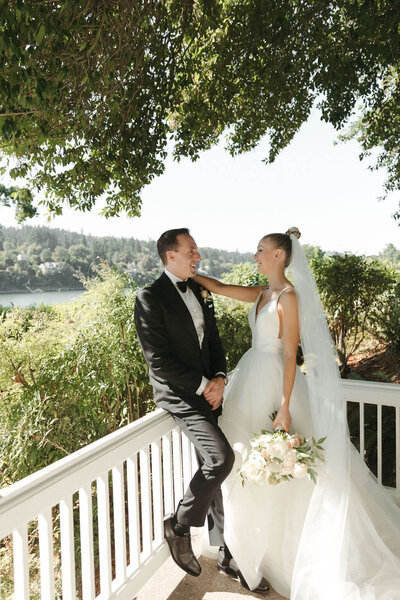 Couple in wedding attire standing together on tree lined balcony