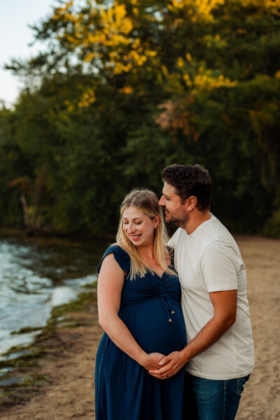 Couple laughing together on the riverbank during an Ottawa mini session at sunset.