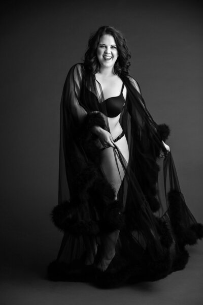 Woman in black fur robe posing in front of gray wall in Baton Rouge boudoir studio. p