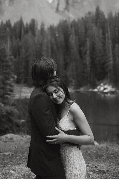 black and white photo of couple hugging in front of water