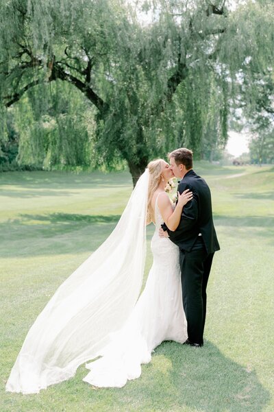 bride and groom kissing on the lawn of Morris Park Country Club