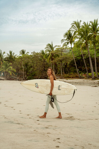 Girl walking on beach with surf board