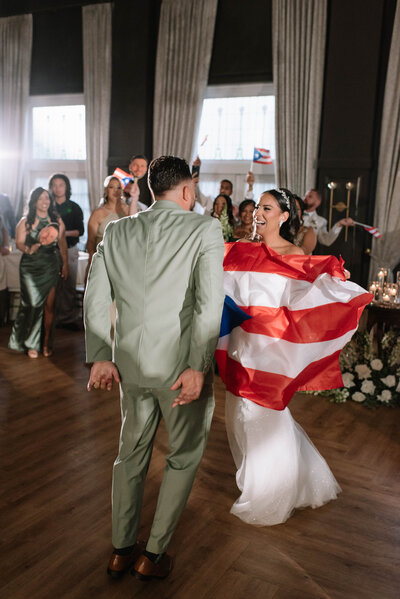 Wedding reception photo at Bear Creek Mountain Resort wedding venue in Macungie, Pa. The groom is picking up the bride and spinning her in celebration of their entrance into their wedding venue while guests cheer around them. The bride and groom are both holding beers and throwing them up in celebration as they share a kiss. Pa wedding reception photos, Pa wedding photos, Pa wedding photographer.