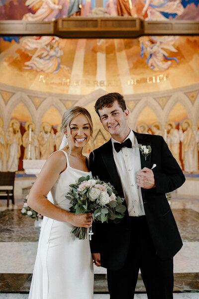 a bride and groom holding hands and smiling
