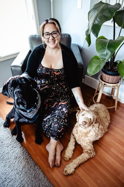 woman sitting in the corner in an arm chair with her two dogs 