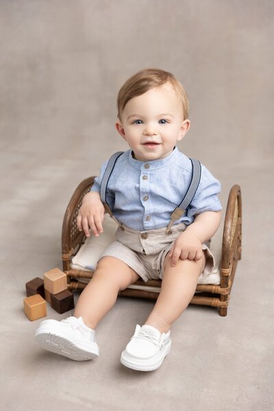 Little boy sitting on wooden bench in studio by baby photographer nj