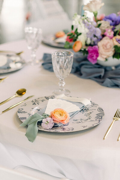 Bridgerton-inspired fan wedding menu displayed on a blue floral plate, showcasing original invitation ideas for a sophisticated celebration.