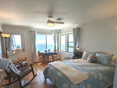 bedroom with blue bedding, rocking chair, and ocean view