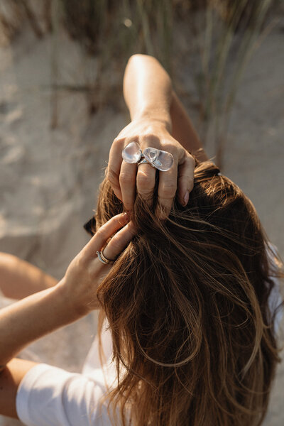 Financially secure woman at the beach with her hands in her hair.