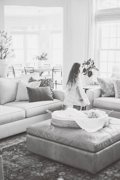 A little girl dancing in family living room near newborn sister 