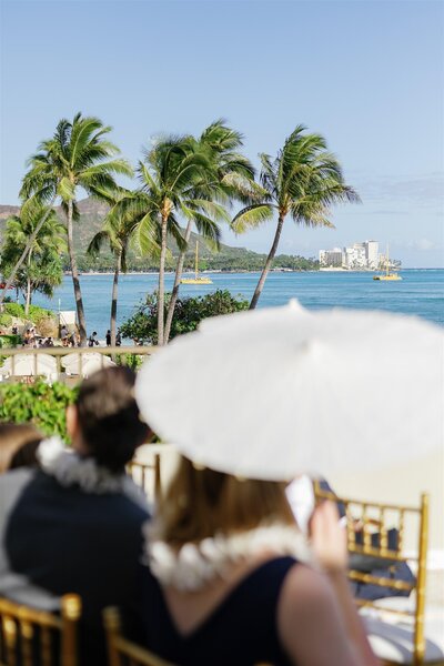 Wedding guests sitting in chairs during a ceremony overlooking the water 