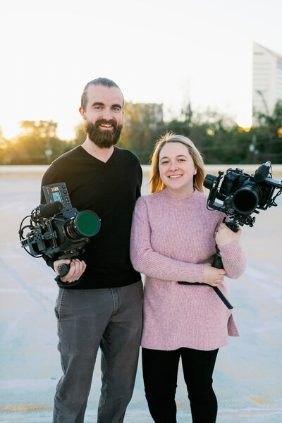 couple holding cinema cameras on downtown parking garage