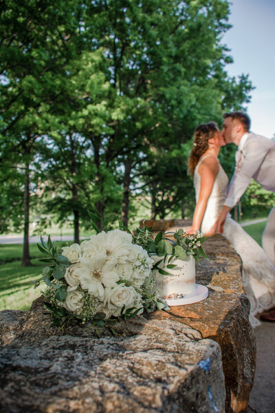 bride and groom kiss behind cake phoenix wedding