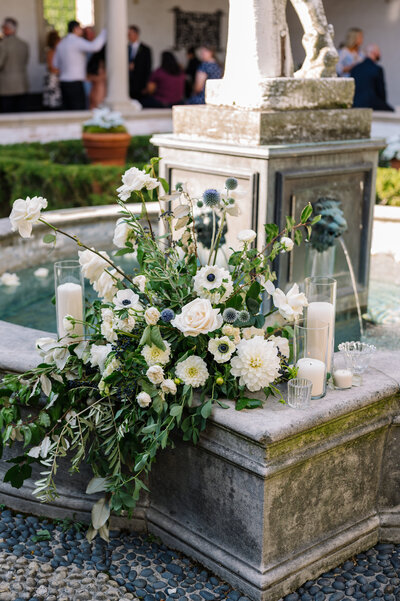 blue and white floral installation with candles sitting on the ledge of the fountain in the mercury courtyard at villa terrace in milwaukee wisconsin