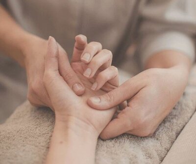Massage therapist gently working on a client’s hand, promoting relaxation and self-care.