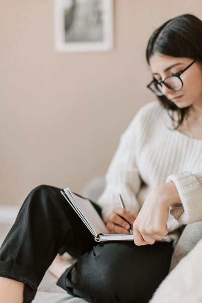 Woman writing in a journal, symbolizing discovering unique strengths in coaching.
