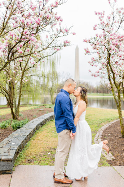 guy in blue shirt and girl in white dress kissing in front of the washington monument