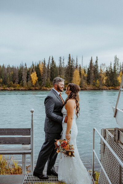 bride and groom looking at each other with lake in the background