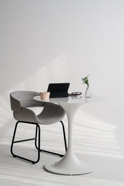 A Denver product photographer takes stock images of a white table with a computer and coffee mug for stock images for branding photo shoot.