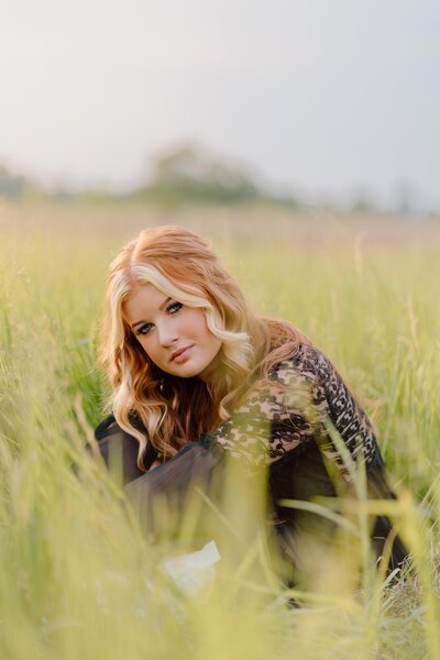 Wisconsin high school senior portrait in field wearing white dress arms above head