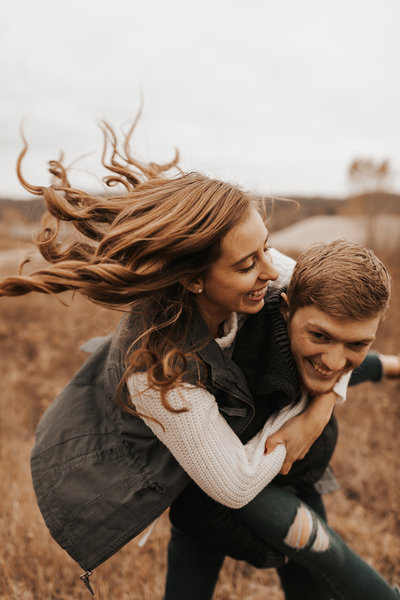 Couple during their midwest engagement session with the girl on the fiances back