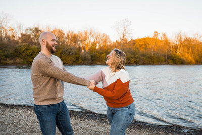 Bride and groom hold hands in front of tall trees at sunset