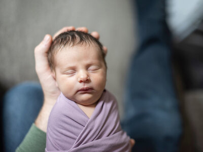 Newborn baby sleeping in dads hands Asheville NC photography at home