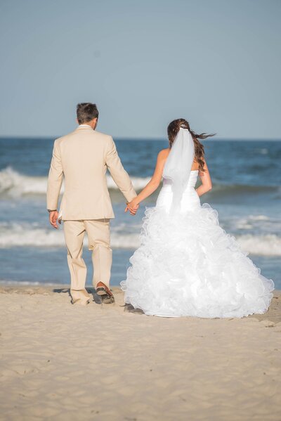 Bride and groom facing ocean