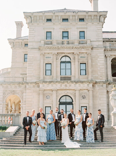 Rhode Island Wedding Photographers | A wedding party poses in formal attire, standing in front of a grand historic mansion. 