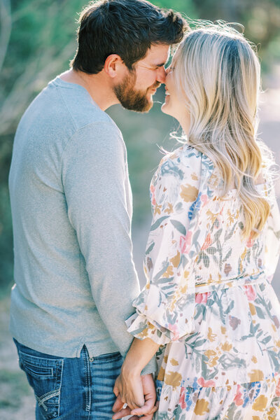 Close up image of man and woman holding hands and standing close with their faces touching