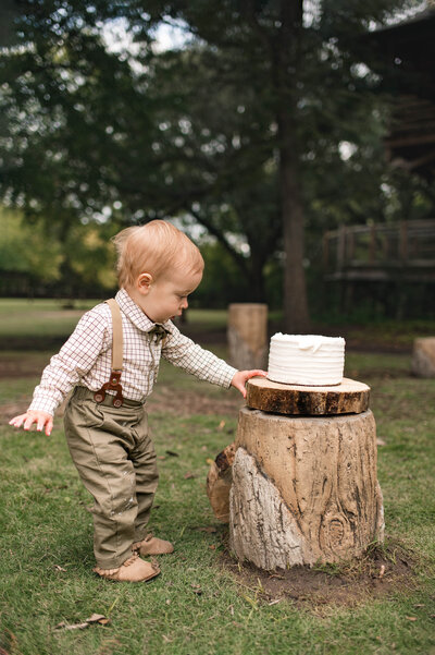 A joyful one-year-old celebrating their 12-month milestone with a cake smash during a photo session in Cypress, Texas.