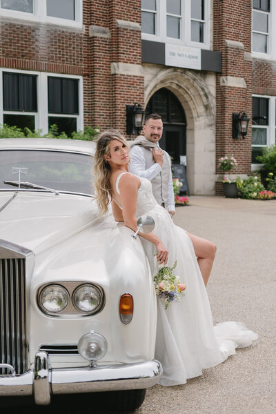bride and groom leaning on classic getaway car