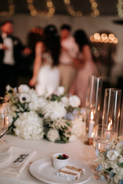 Photo of the table at a wedding with people dancing in the background.