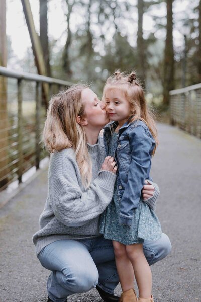 A family of four stand on a bridge smiling with arms around each other