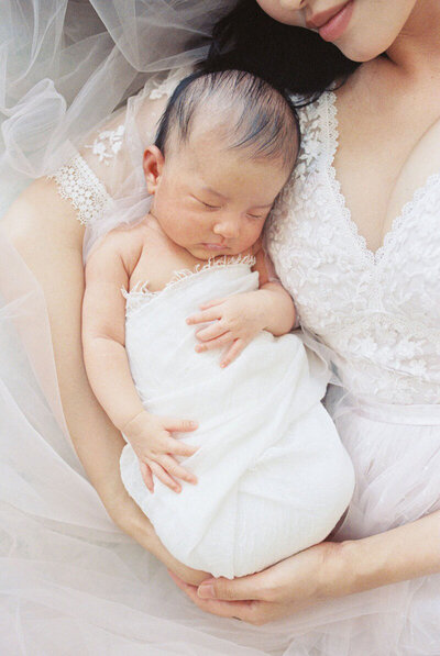 Baby sleeping in mother's arms for their photo session with Bay Area newborn photographer
