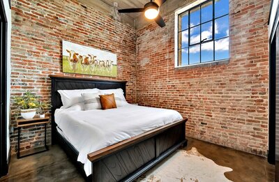 Bedroom with King size bed in this three-bedroom, two-bathroom industrial modern loft condo in the historic Behrens building in downtown Waco, TX.