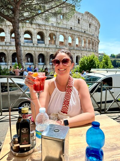 Anne Traveling in Europe with a Drink at a Table