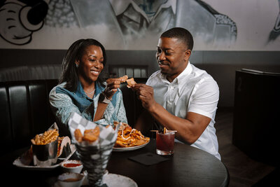 Loaded nachos topped with savory ingredients, crispy seasoned fries served with a creamy dipping sauce, and vibrant cocktails, all set on a sleek bar counter.