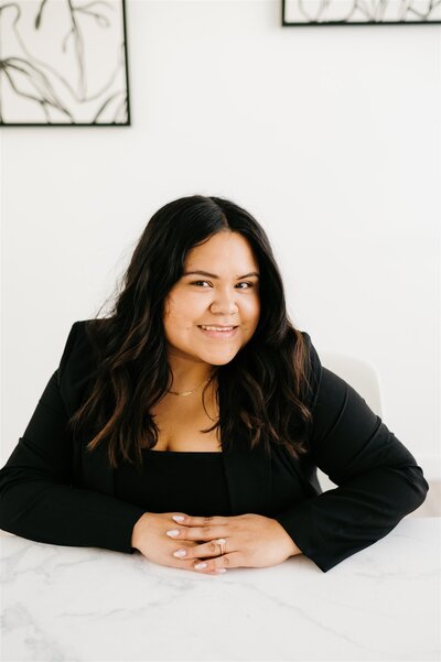 Charlottesville wedding photographer posing in a studi oat a white table wearing a black blazer and dress