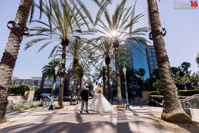Newly married couple pose under the palm trees by Casa Bella Event Center in Anaheim