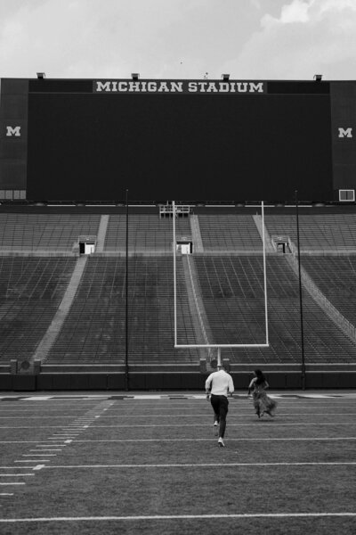 A couple running together on a football field 