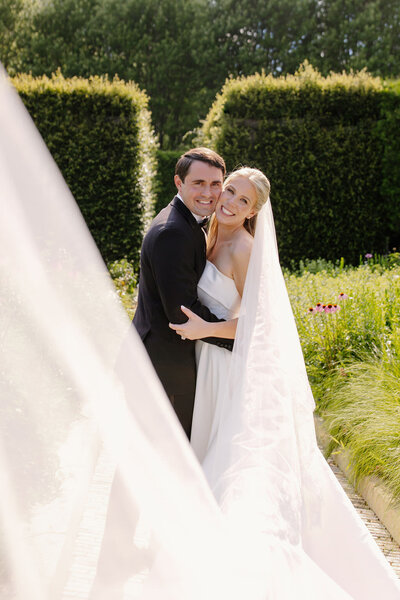Bride and groom embrace in Chicago park as wedding veil blows in the breeze