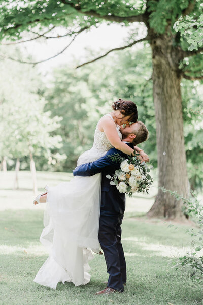 groom picking bride up as she looks down at him